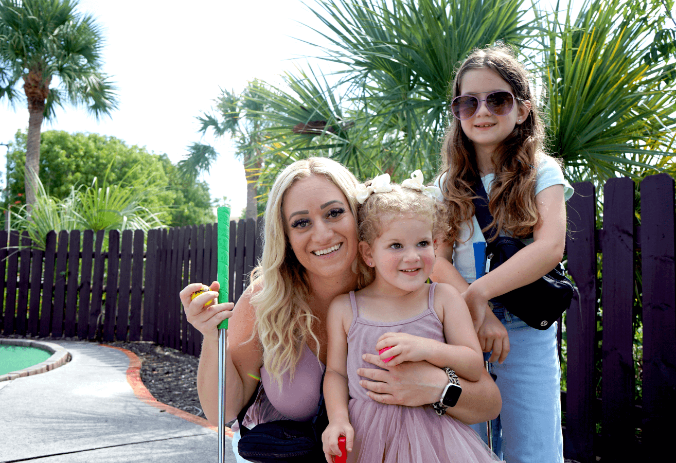 Mother and two daughters on mini golf course