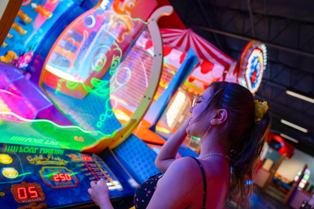a girl plays an arcade game with bright lights