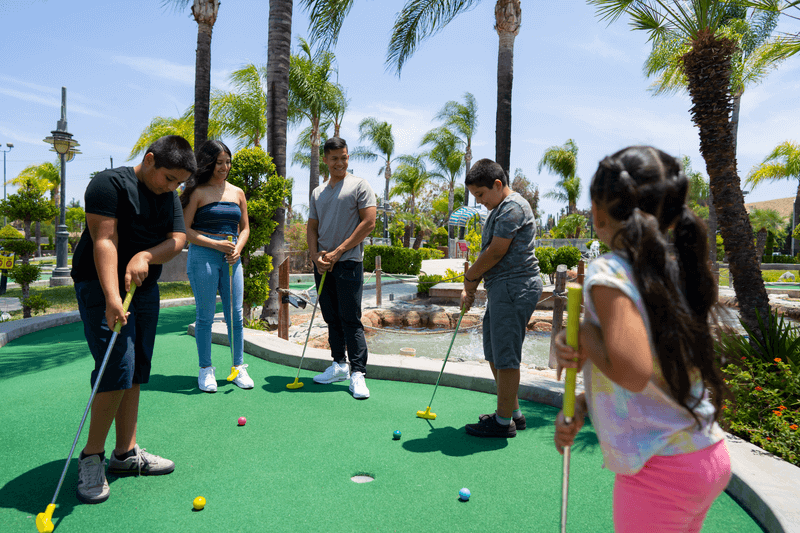 Family playing mini golf in Boomers