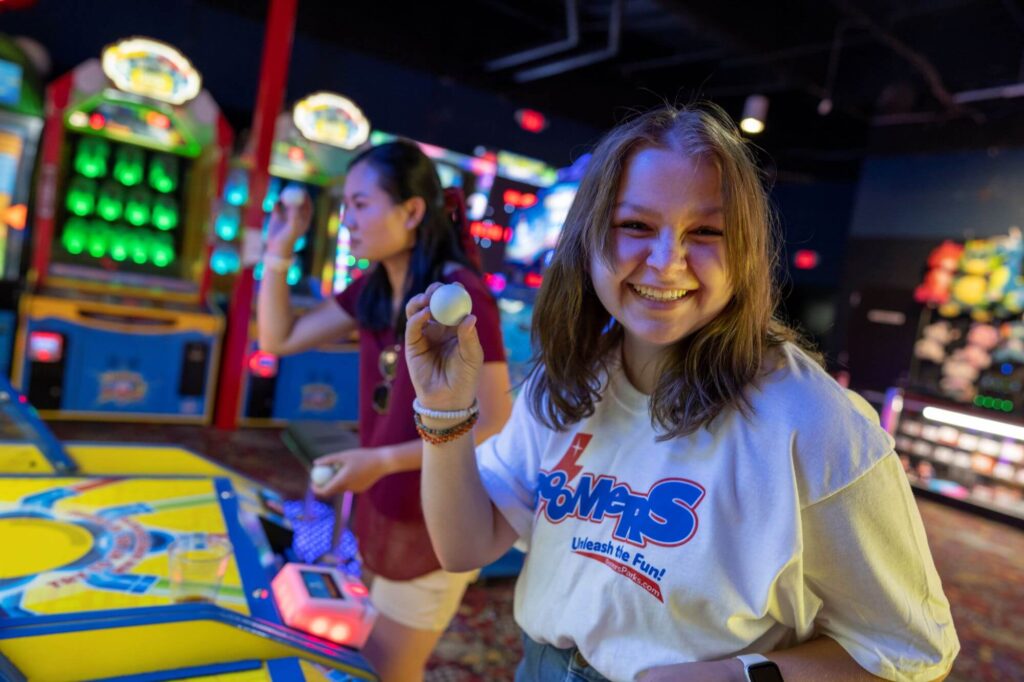 Girl playing ball throw arcade game at Boomers